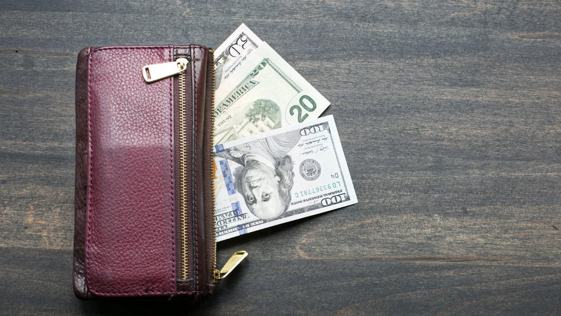 red wallet with cash laid on a dark wooden table 